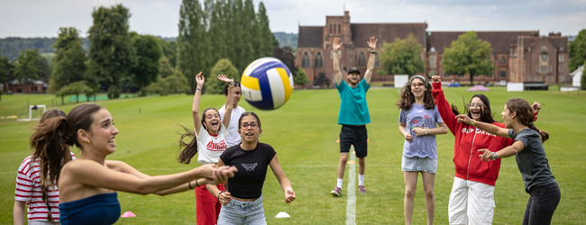 Girls and boys play volleyball on a sports ground of Ardingly College